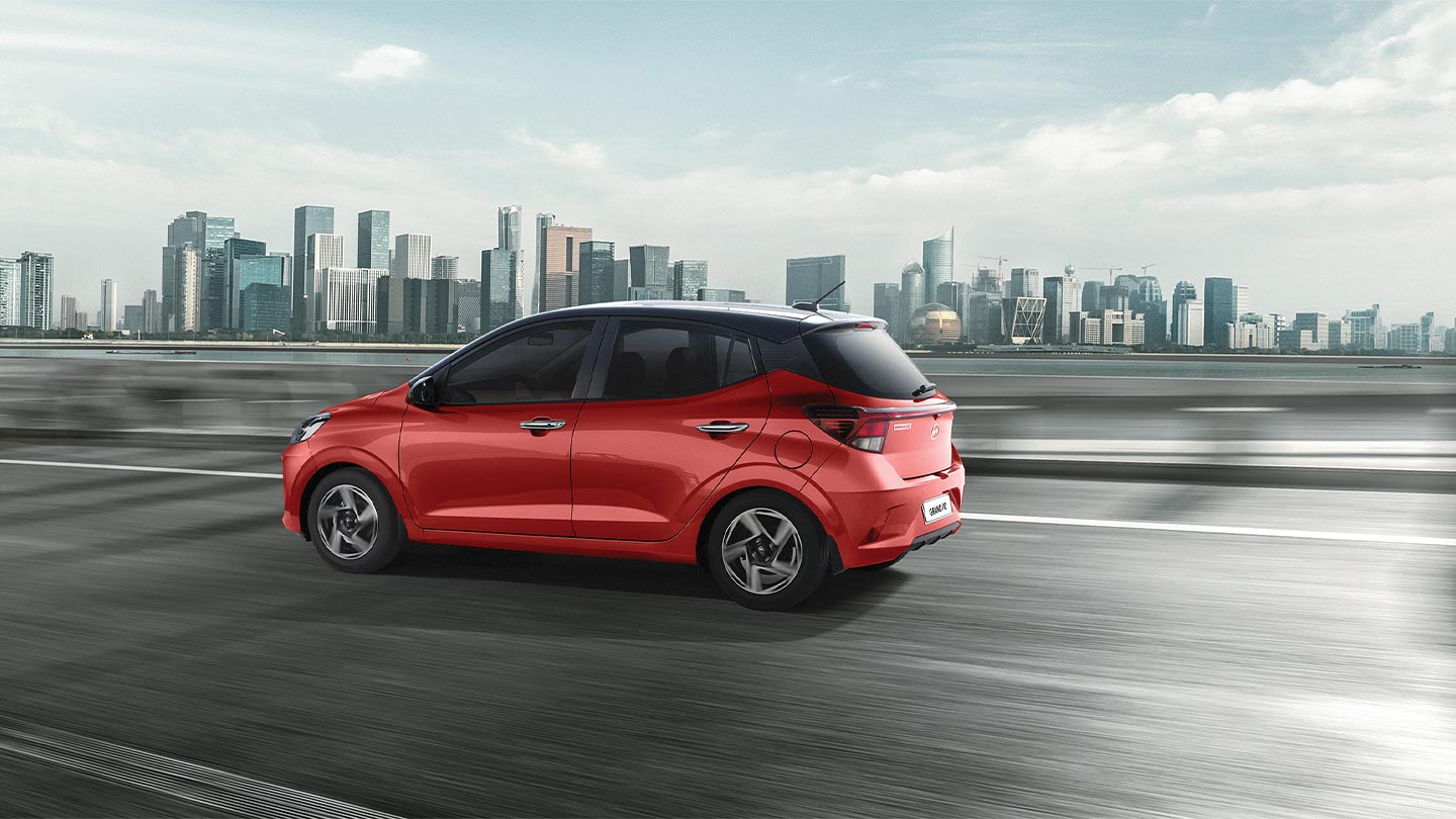 Vista lateral de Grand i10 Hatchback 2026 color rojo circulando por la ciudad