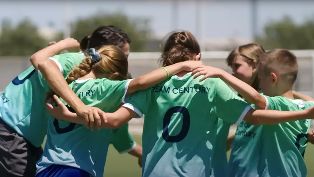 Ni&ntilde;as abrazandose con camisetas de goal century dentro de un partido