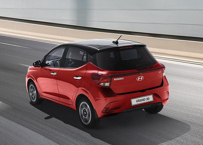 Vista tres cuartos trasera de Grand i10 Hatchback 2026 color rojo en un túnel